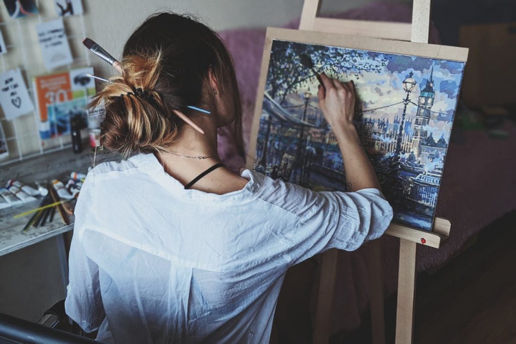 a woman painting a cityscape